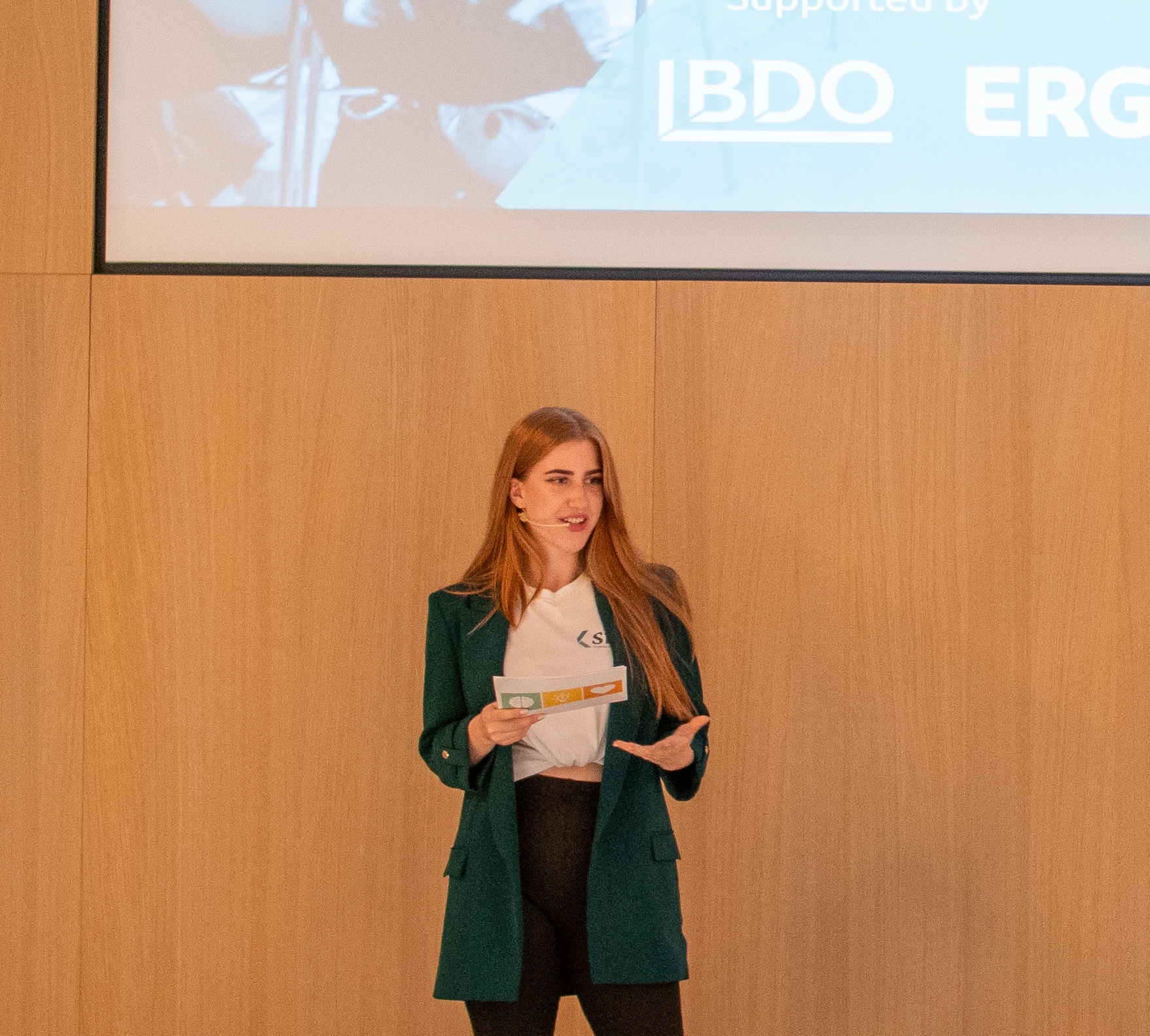 Eva-Maria Schneider moderating SIC Connect 2025 in a green blazer with cue cards