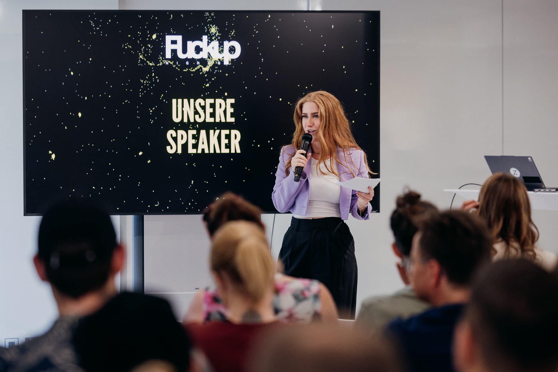 Eva-Maria Schneider moderating FuckUp Night Graz in front of a seated audience