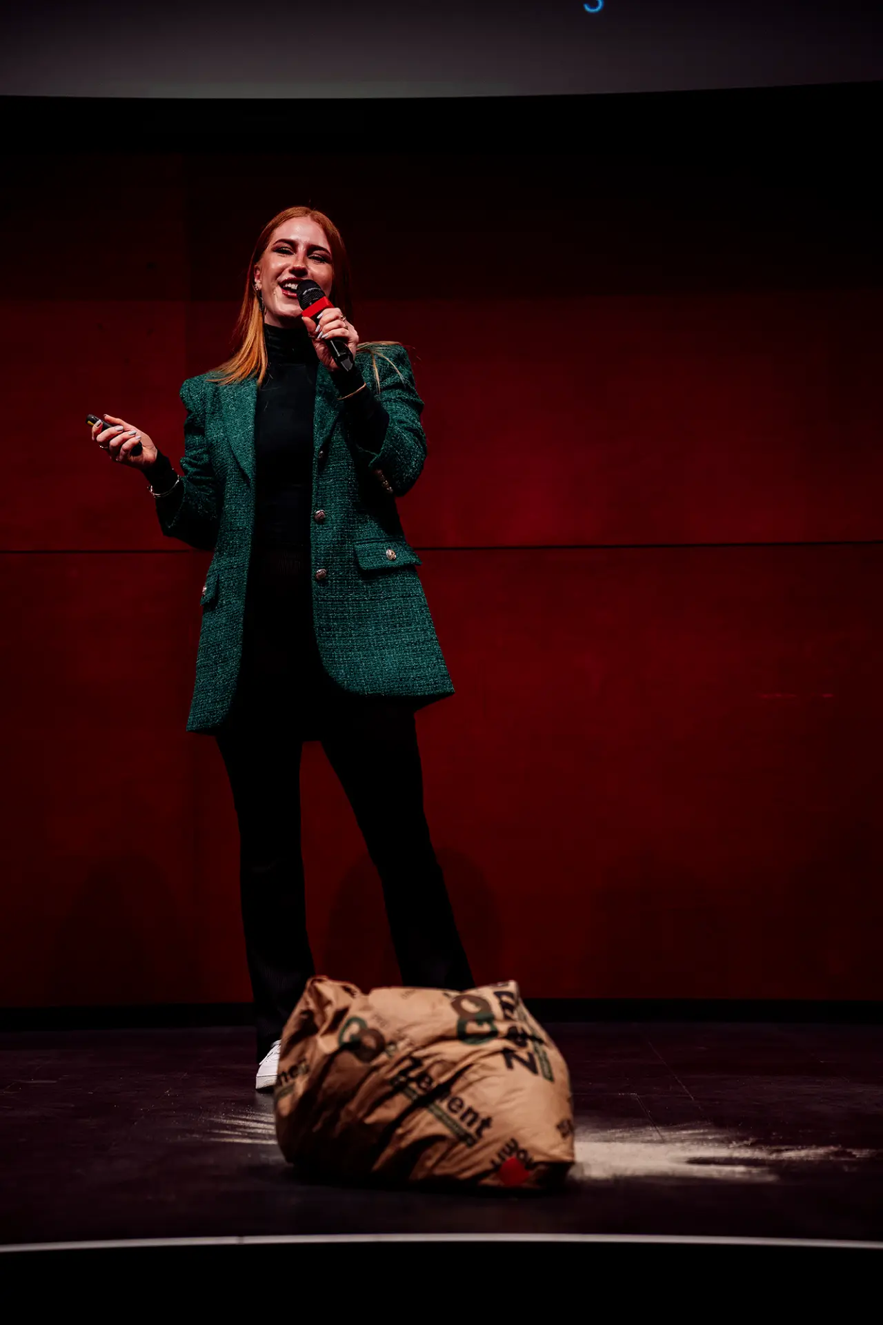 Eva-Maria Schneider pitching on a red-lit stage with a cement bag beside her